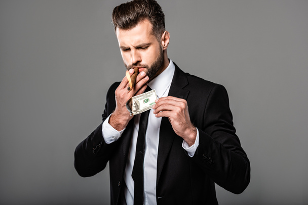 rich businessman lighting up cigar from burning dollar banknote isolated on grey - Photo, Image