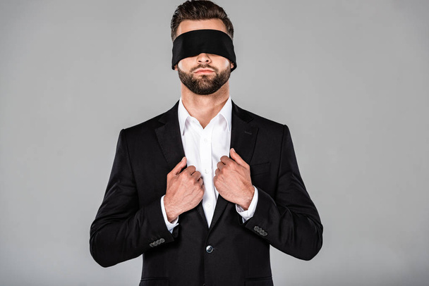 stylish handsome blindfolded businessman in black suit isolated on grey - Foto, imagen