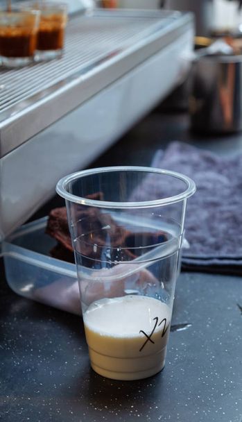 Márvány asztal tetején. Átlátszó műanyag csésze. Tejfehér tiszta tej normál hőmérsékletű tejet. Kávé-italok készítése szobahőmérsékleten - Fotó, kép