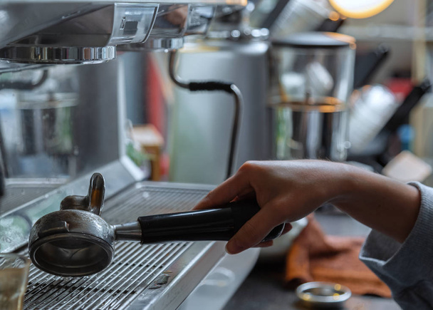 De barista reinigt de gereedschappen. De barista reinigt de handgreep van de koffiemachine op de koffie console. - Foto, afbeelding