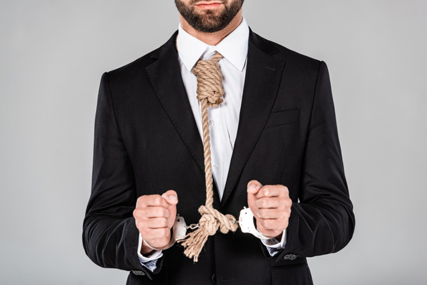 osittainen näkymä liikemies musta puku ja käsiraudat silmukka kaulassa eristetty harmaa
 - Valokuva, kuva
