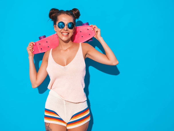 Young beautiful sexy smiling hipster woman in sunglasses.Trendy girl in summer knitted cardigan topic ,shorts.Positive female going crazy with pink penny skateboard,isolated on - Foto, immagini