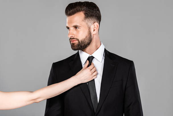 donna toccare cravatta su uomo d'affari in abito nero isolato su grigio
 - Foto, immagini