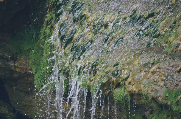 Φωτεινός καθαρός καταρράκτης σε σκουρόχρωμα πράσινα βρύα στο δάσος του φθινοπώρου - Φωτογραφία, εικόνα