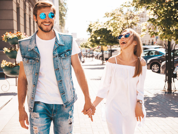 Smiling beautiful girl and her handsome boyfriend. Woman in casual summer dress and man in jeans clothes. Happy cheerful family.Hold each other hands and walk - Φωτογραφία, εικόνα