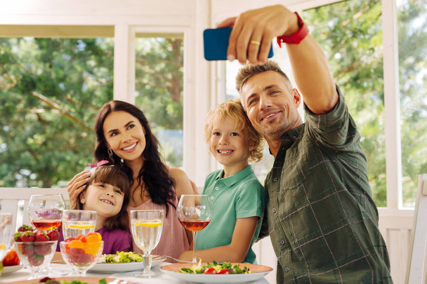 Mann nimmt sein Smartphone beim Selfie mit Familie - Foto, Bild