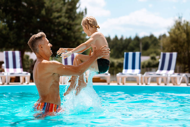 Daddy throwing his son into water while having fun in pool - Photo, Image