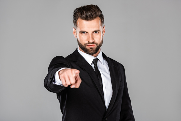 exitoso hombre de negocios en traje negro apuntando con el dedo a la cámara aislado en gris
 - Foto, imagen
