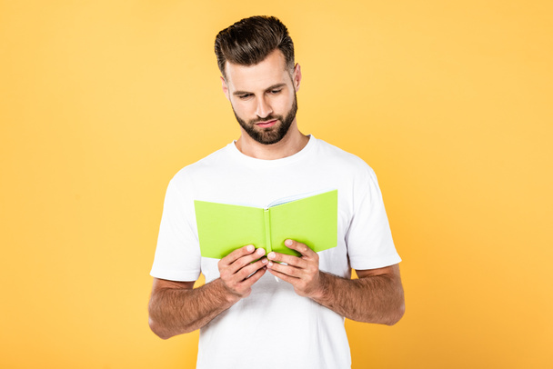 man in wit t-shirt lezen boek geïsoleerd op geel - Foto, afbeelding
