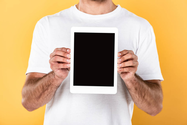 cropped view of man in white t-shirt showing digital tablet with blank screen isolated on yellow - Fotoğraf, Görsel