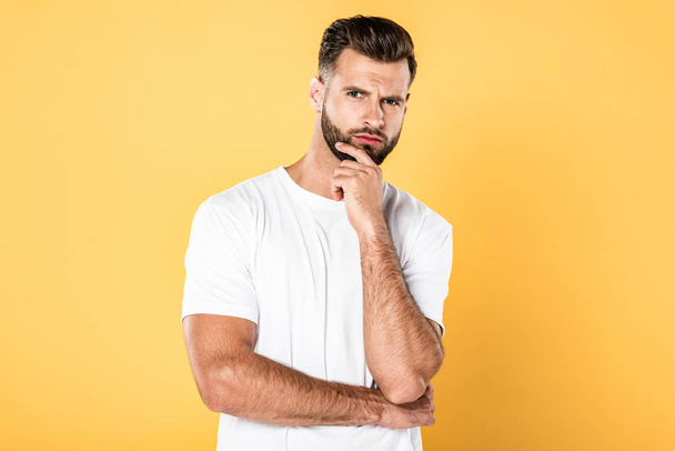 pensive handsome man in white t-shirt isolated on yellow - Photo, Image