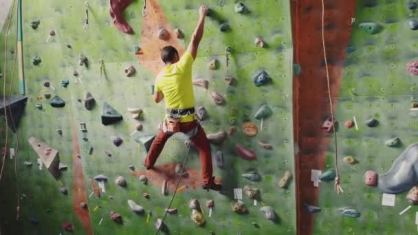 Klimmen sportactiviteit concept: man klimmer op de muur. Indoor klimmen sportactiviteit concept: man klimmer op kunstmatige klimmuur - Video