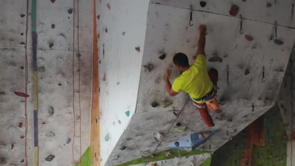 Mladý muž Rock horolezec šplhá na vnitřní šplhání do tělocvičny. štíhlý krasavče cvičení v interiérové tělocvičně - Záběry, video