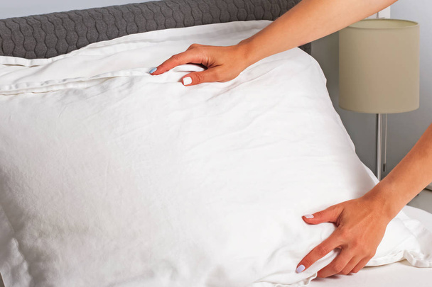 Housekeeper changing the linen and putting pillows on the bed with fresh clean white bedding. - Foto, Bild