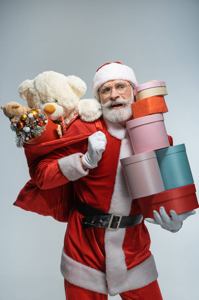 Mature Santa Claus holding sack and gift box - Foto, afbeelding