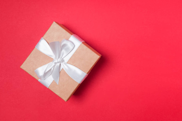 Giftbox with white ribbon on the red background - Zdjęcie, obraz