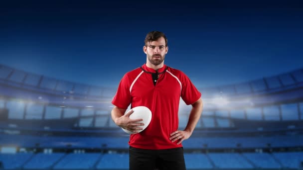 Animation of a Caucasian male rugby player holding a ball and looking to camera with floodlit stadium in the background - Materiał filmowy, wideo