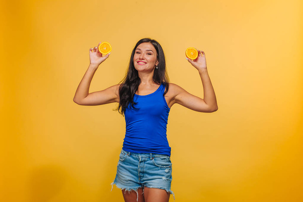 Chica sobre un fondo amarillo con naranjas
. - Foto, imagen