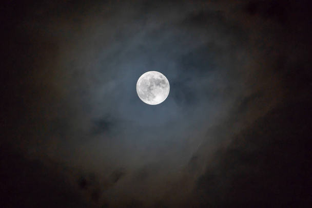 Luna llena en la noche oscura brillando en el cielo en el día nublado
. - Foto, Imagen