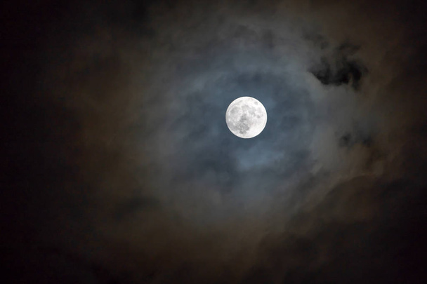 Luna llena en la noche oscura brillando en el cielo en el día nublado
. - Foto, imagen
