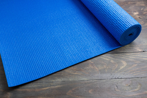 Blauwe yoga mat op houten achtergrond. Apparatuur voor yoga. Concept  - Foto, afbeelding