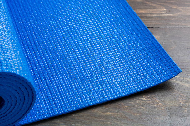 Esterilla de yoga azul sobre fondo de madera. Equipo para yoga. Concepto
  - Foto, imagen