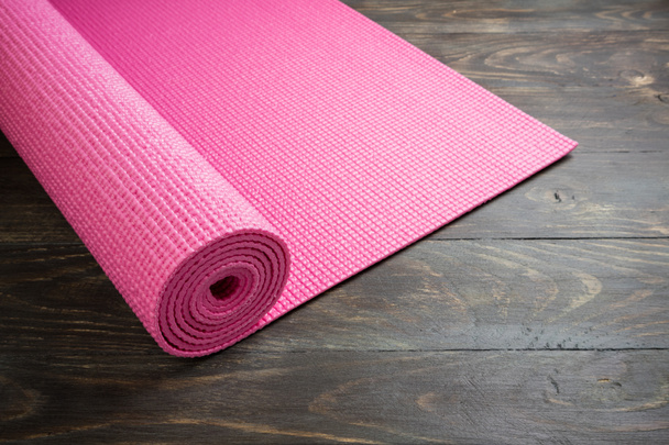 Pink yoga mat on wooden background. Equipment for yoga. Concept  - Photo, Image