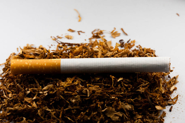 Sigaretten op de hoeveelheid geraspte tabak, geïsoleerd op een zwarte achtergrond. Tabak kan ziekten veroorzaken. - Foto, afbeelding
