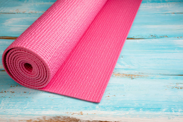 Roze yoga mat op blauwe houten achtergrond. Apparatuur voor yoga. Con - Foto, afbeelding