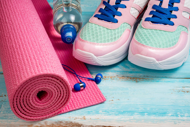 Pink yoga mat, sport shoes, bottle of water and earphones on blu - Fotoğraf, Görsel