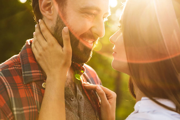 alegre complacido romántico joven amante pareja caminando al aire libre en un verde parque natural bosque besos
. - Foto, imagen
