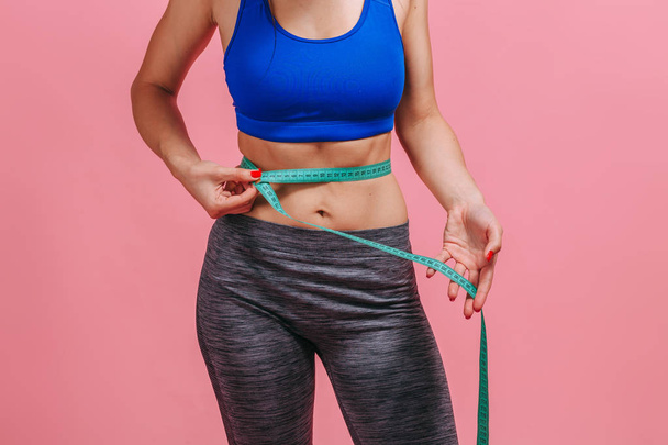 girl measures a waist on a pink background - Photo, Image
