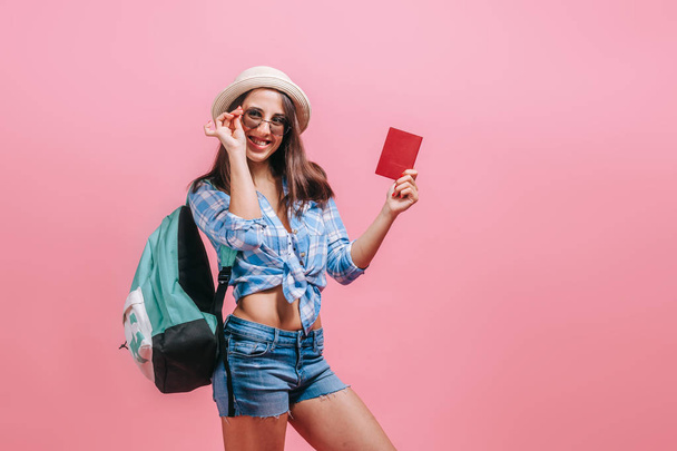 The girl tourist with backpack is showing passport on a pink bac - Foto, Imagem