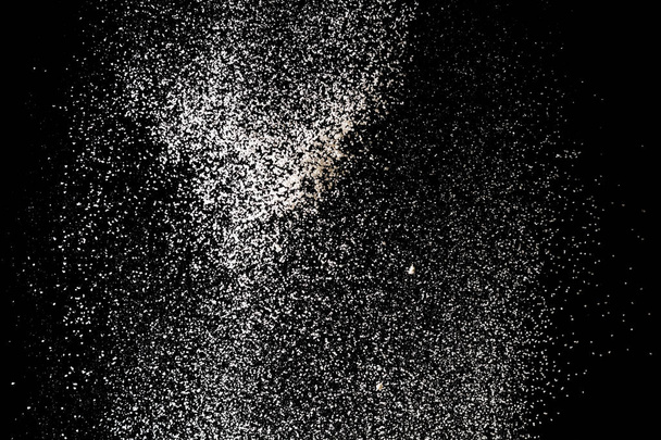 Polvere bianca spruzzata isolata su fondo nero. Polvere esplosiva
 - Foto, immagini