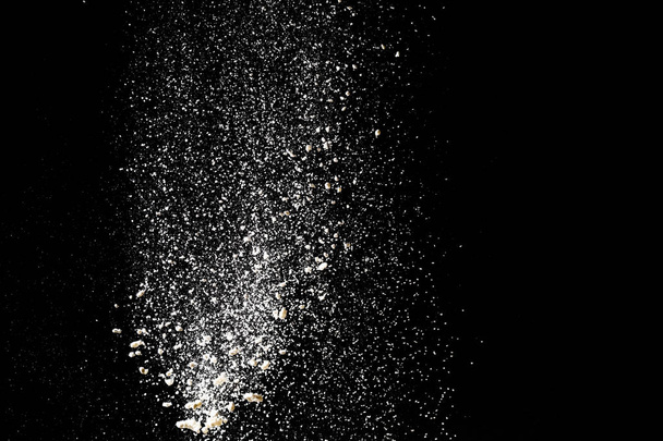 Mąka przesiedlenia na czarnym tle. Izolat biały proszek Splash - Zdjęcie, obraz