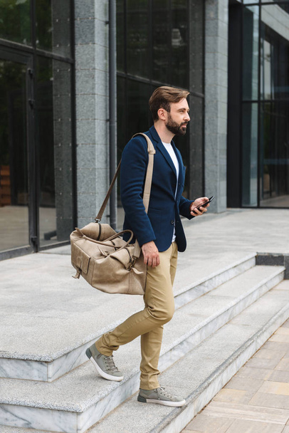 Attractive young bearded man wearing jacket walking - Fotoğraf, Görsel