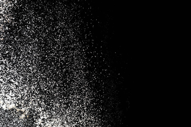 Просеивание муки на черном фоне. Брызги белого порошка
 - Фото, изображение