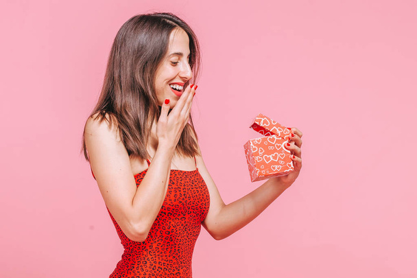 das Mädchen erhielt eine Schachtel mit einem Geschenk und freut sich über einen rosafarbenen Rucksack - Foto, Bild