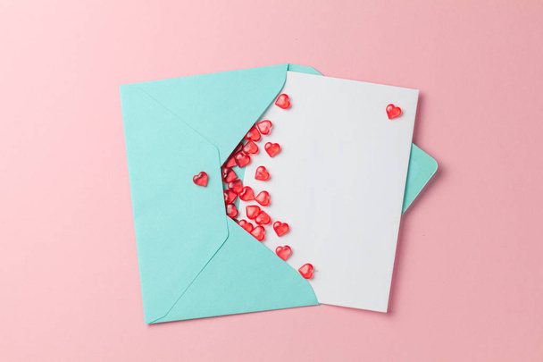 Любовное письмо с красными сердцами. Бланк с местом для текста на открытке. Зеленый конверт на розовом фоне. mock-up
 - Фото, изображение