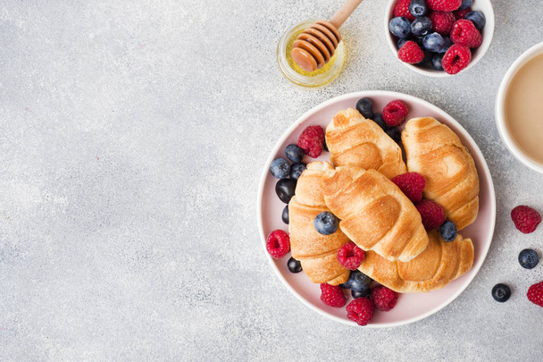Croissants with fresh raspberries and blueberries on grey concre - 写真・画像