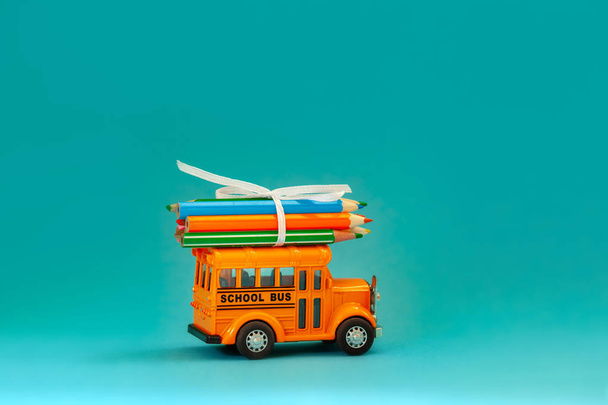 Yellow retro school bus with pencils on roof on blue background. Concept education and back to school. - Foto, Bild