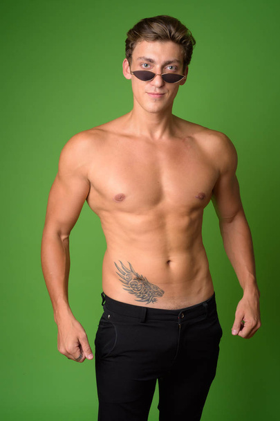 Portrait of young handsome shirtless man wearing sunglasses - Foto, Imagem