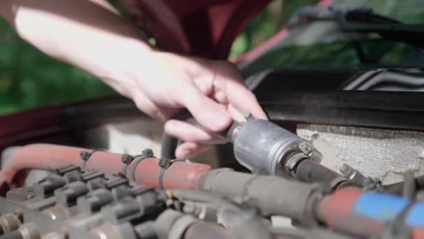 Close-up van de handen van een man die zelfstandig het LPG-filter in zijn auto vervangt. Jonge kerel repareren auto in outdoor. De auto brak op de weg. 4k-beeldmateriaal. - Video