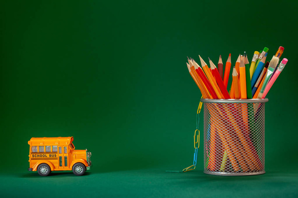 Education and back to school concept. Yellow retro school bus and pencils in basket on dark green background. - Φωτογραφία, εικόνα
