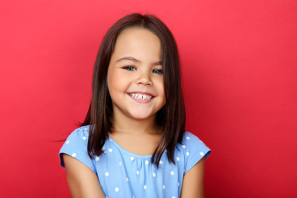 Beautiful little girl in blue dress on red background - Foto, Imagen