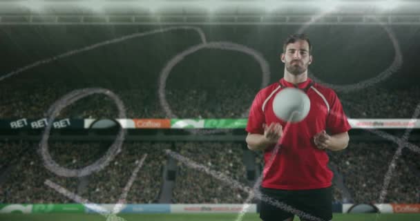 Animation of a Caucasian male rugby player standing, playing with a ball and looking to camera with hand drawn game plan in the foreground and sports stadium in the background 4k - Video, Çekim