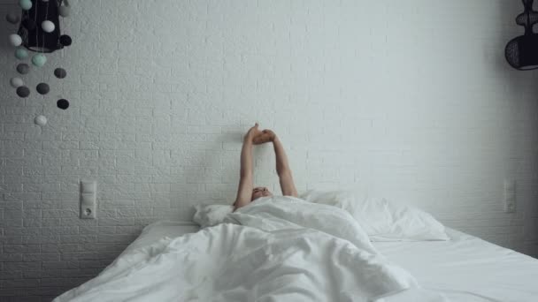 Kobieta przebudzenie w wygodnym przytulnym łóżku rozciągania i wstaje. - Materiał filmowy, wideo
