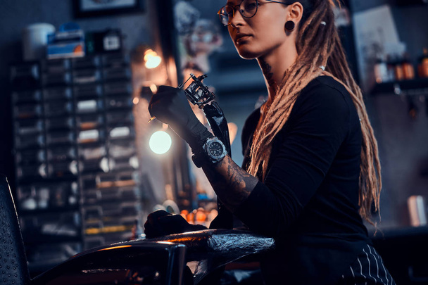 Portret atrakcyjnej młodej kobiety z maszyną tatuażu w rękach - Zdjęcie, obraz