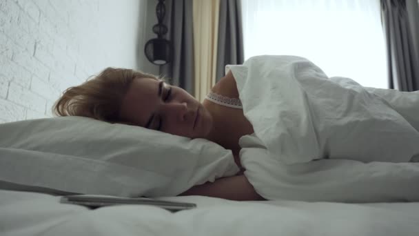Śpiąca kobieta włącza alarm wyłączony podczas przebudzenia rano. - Materiał filmowy, wideo