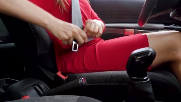 Γυναίκα με κόκκινο φόρεμα στερέωσης ζώνη ασφαλείας του αυτοκινήτου ενώ κάθεται στο εσωτερικό του οχήματος πριν από την οδήγηση - Πλάνα, βίντεο